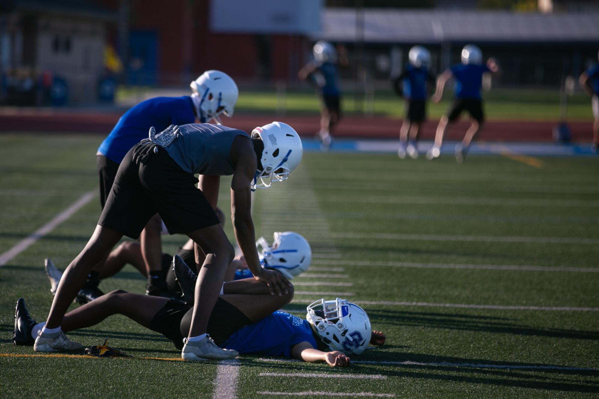Culver City High football players stretch in pairs six feet apart during the first official football practice.
