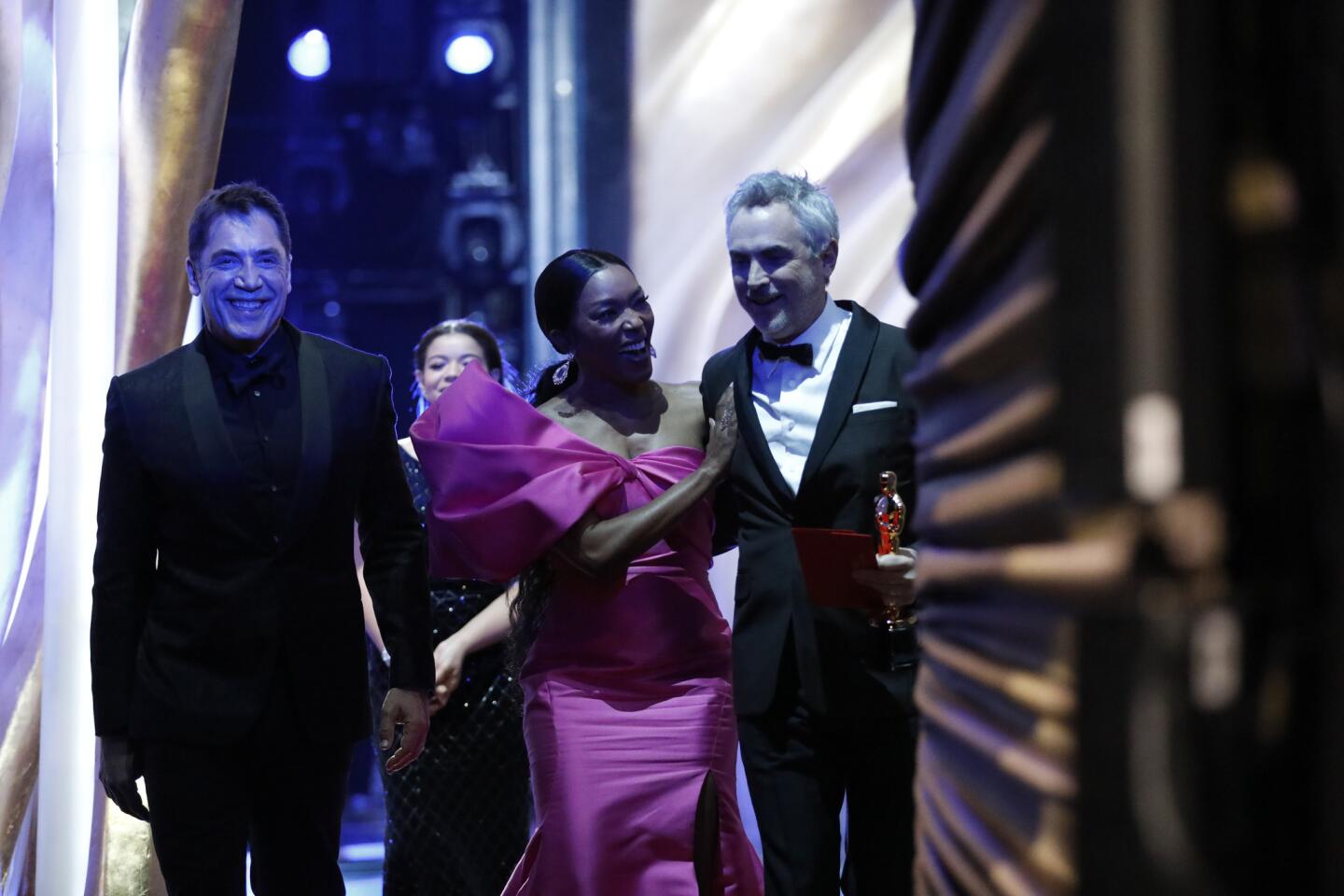 Presenters Javier Bardem, left, and Angela Bassett accompany Alfonso Cuarón after his win for foreign-language film.