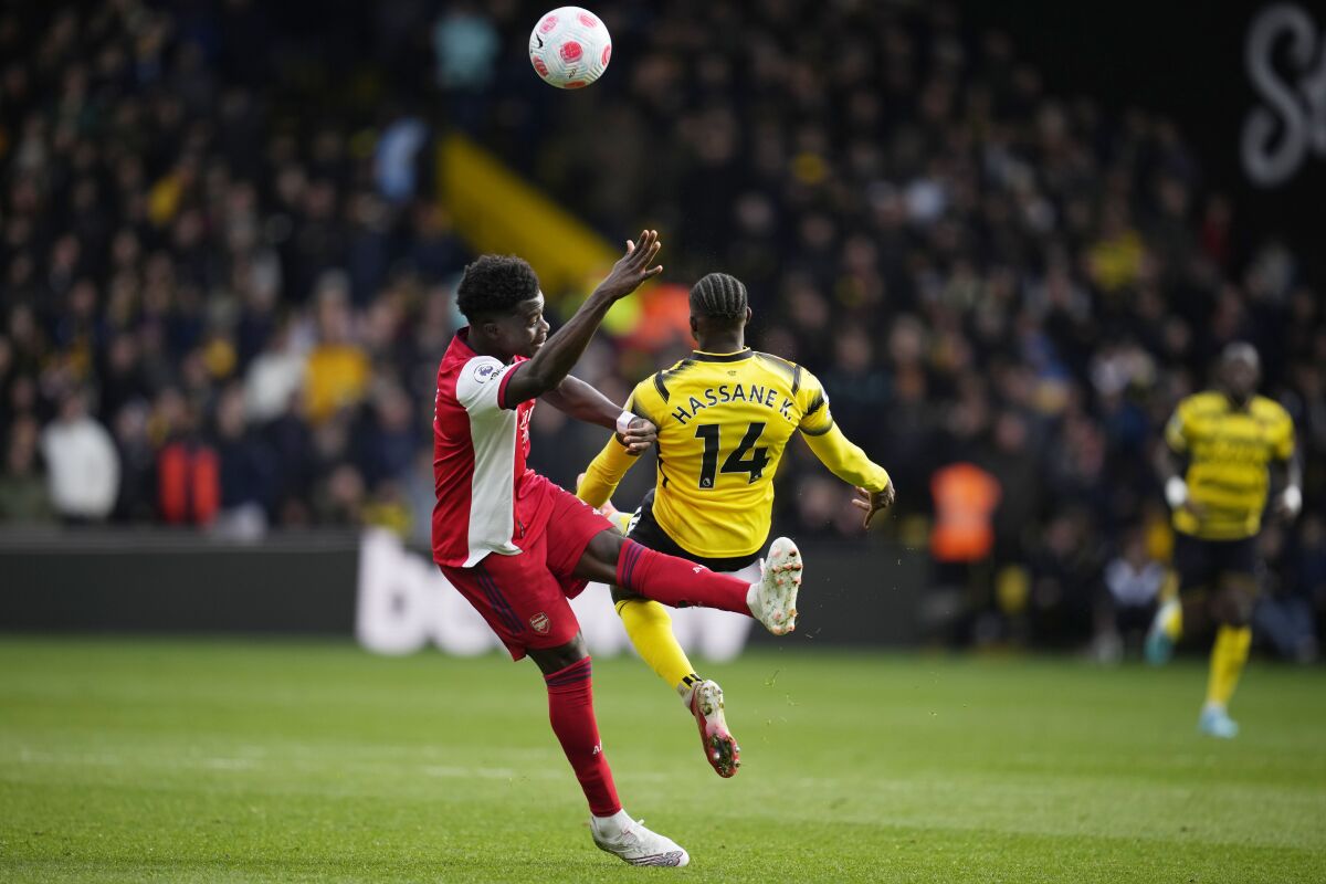 Arsenal's Bukayo Saka, left, and Watford's Hassane Kamara jump for the ball during the English Premier League soccer match between Watford and Arsenal, at Vicarage Road, Watford, England, Sunday, March 6, 2022. (AP Photo/Matt Dunham)
