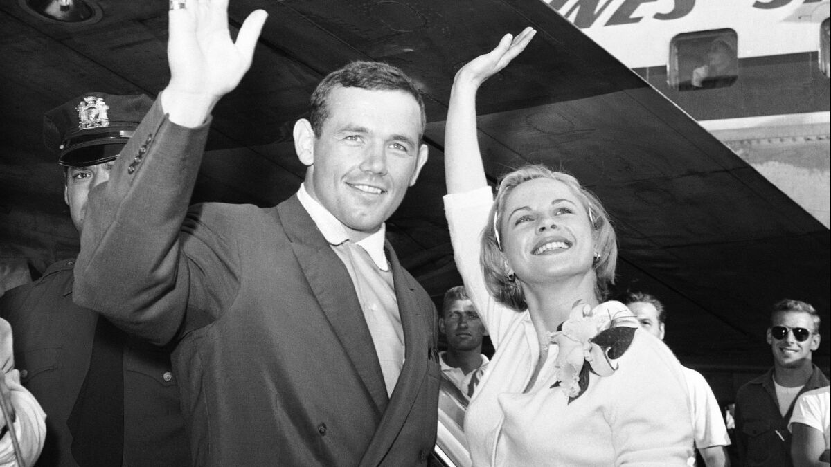 Swedish actress Bibi Andersson and directort Ingemar Johansson wave for photographers at New York's Idlewild Airport on July 3, 1959.