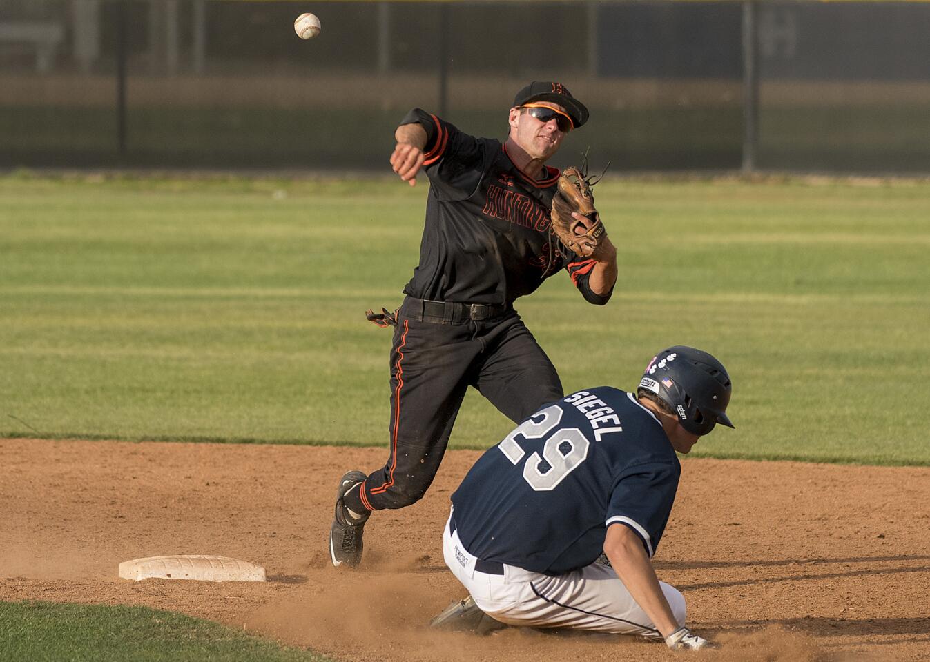 Huntington Beach's Luke Glascoe gets the force at second against Newport Harbor's Brad Siegel and turns the double play to end the game on Wednesday, April 11.