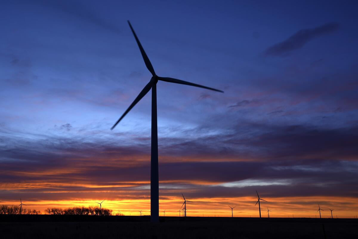 Wind turbines are silhouetted against the sky at dawn near Spearville, Kan.