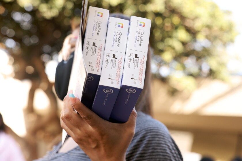 Glenda Cutzan carries COVID-19 test kits outside Greenwood Elementary School in Montebello