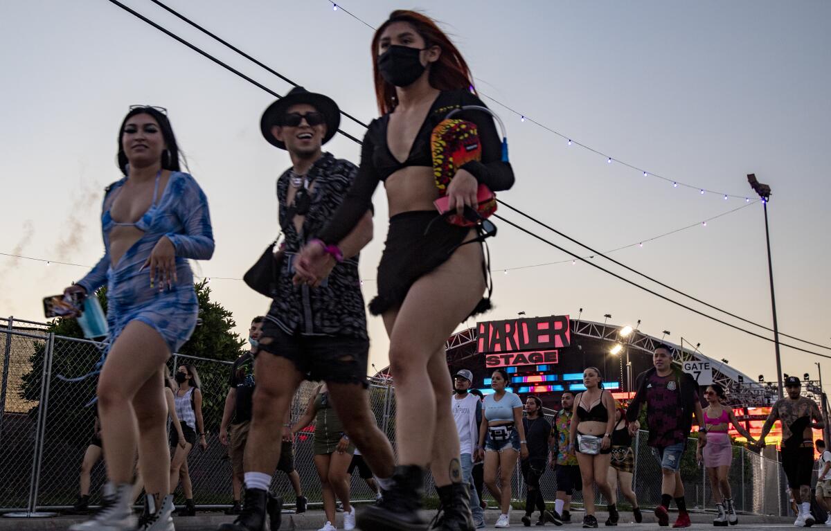 A group of people, most without a mask, walk