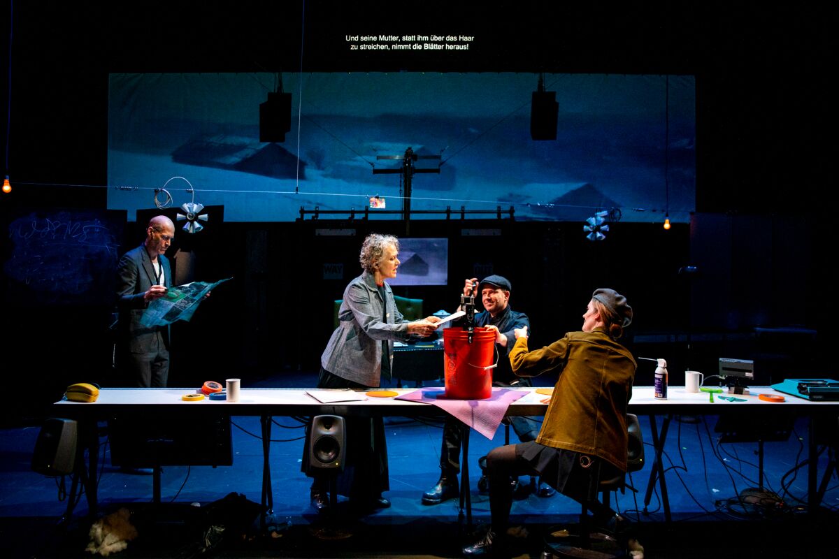 Four performers onstage, along a long table.