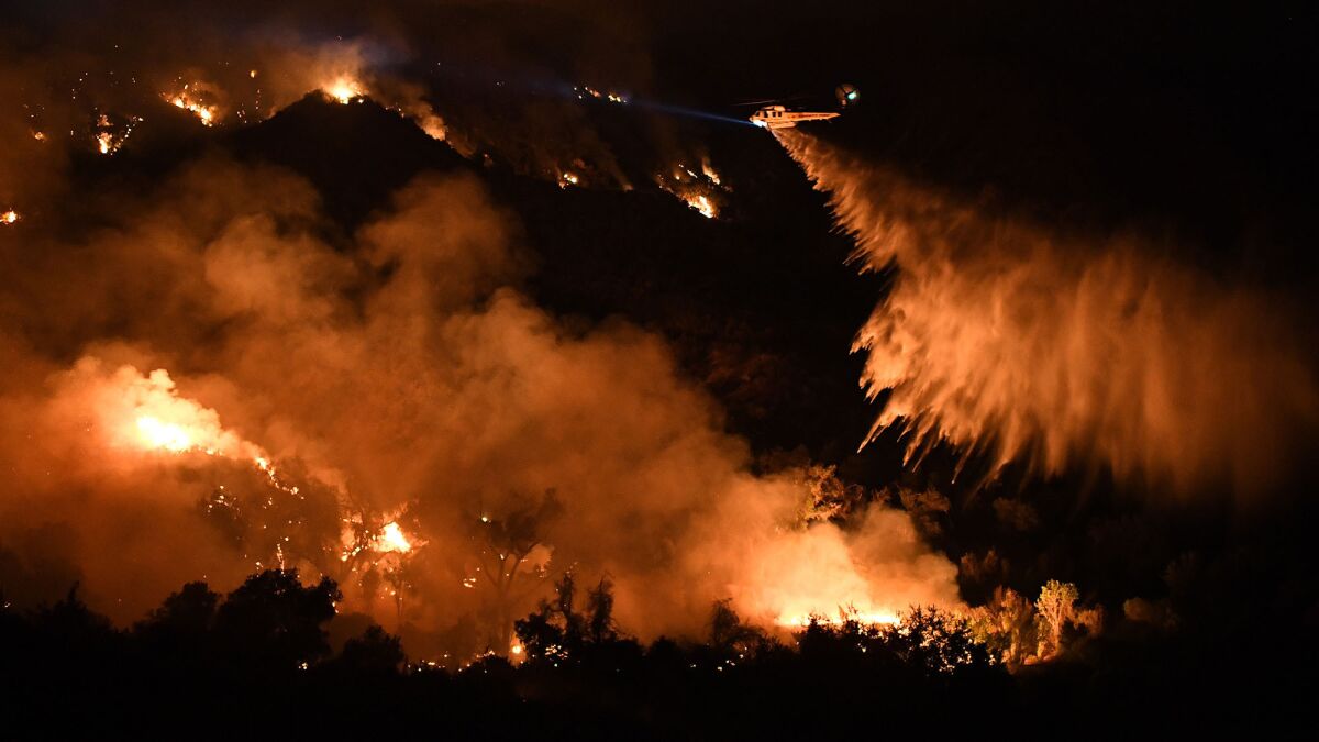 A helicopter makes a water drop on the Sand fire along Placerita Canyon Road near Santa Clarita on Sunday night.