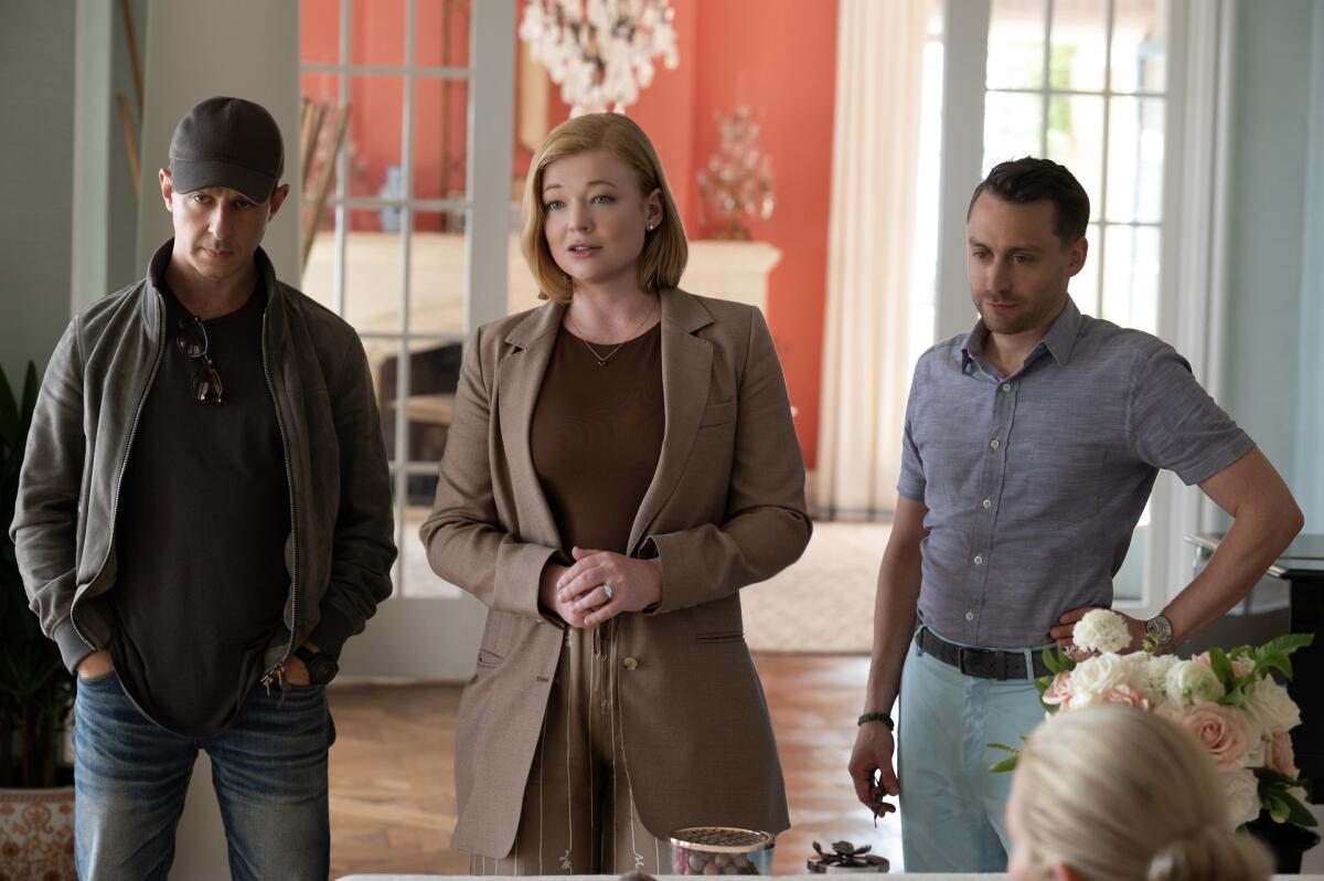 Jeremy Strong, Sarah Snook and Kieran Culkin stand in a living room talking to someone out of frame in "Succession."