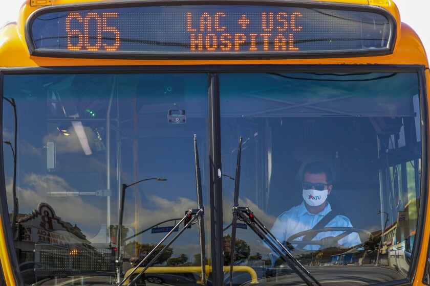 A Metro driver operating the Line 605 bus on Soto Street in Boyle Heights wears a mask bearing the logo of the Amalgamated Transit Union. 