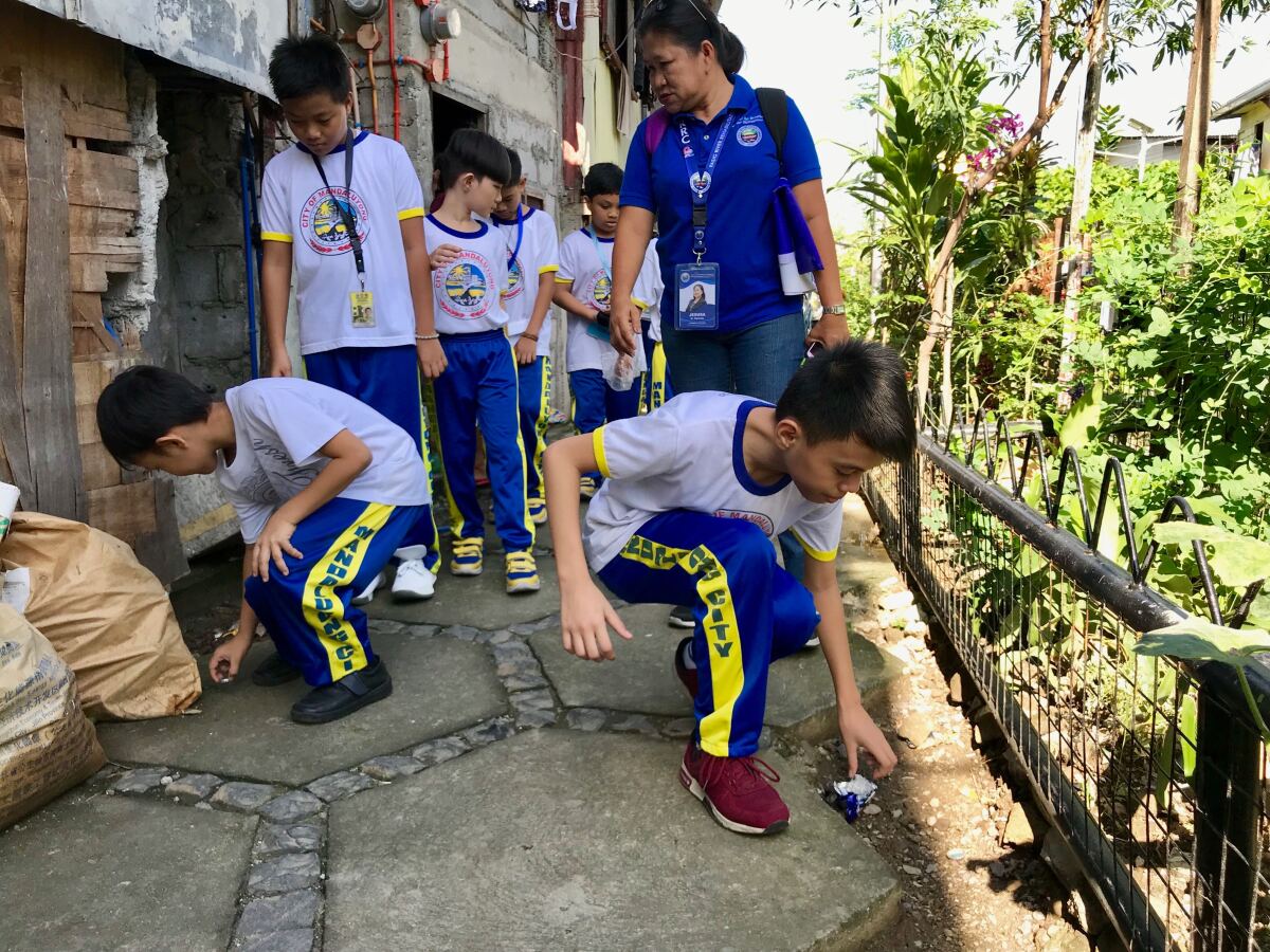 Elementary school students collect litter from along Maytunas Creek, a tributary of the heavily polluted Pasig River in Manila.