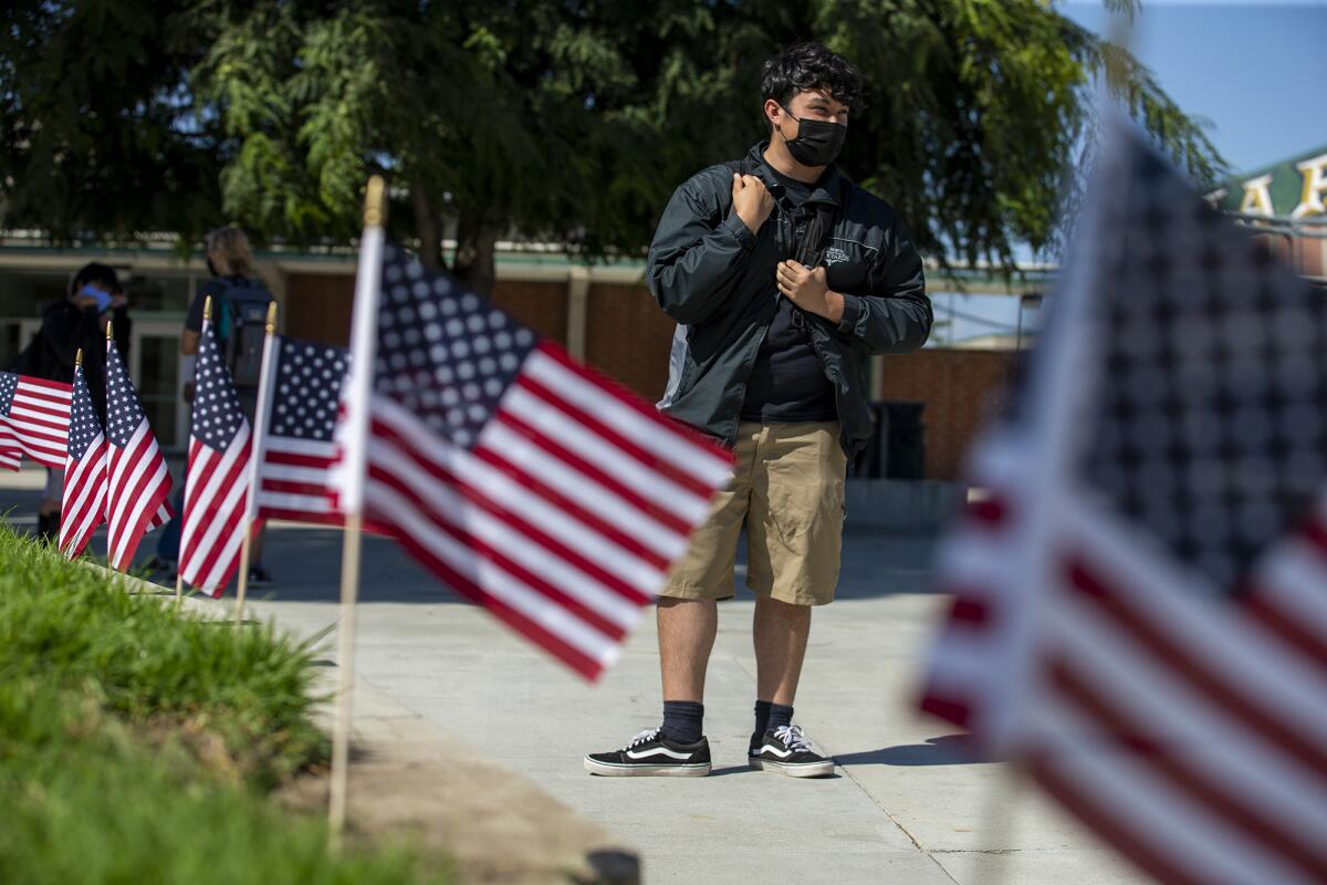Sam Derusse, 17, a student at Edison High, stands in middle of school near 500 American flags.