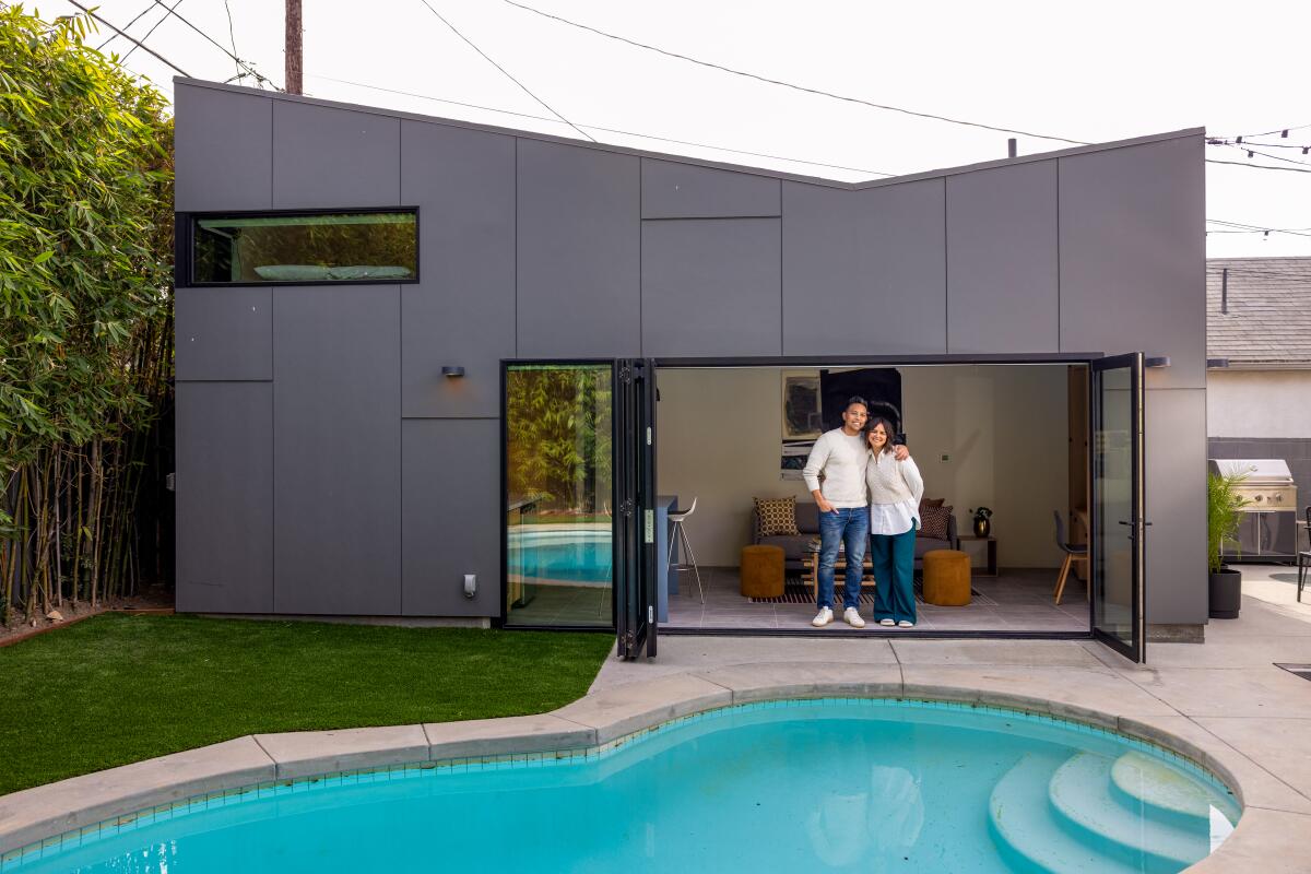 Couple stand outside their modern ADU in front of a pool