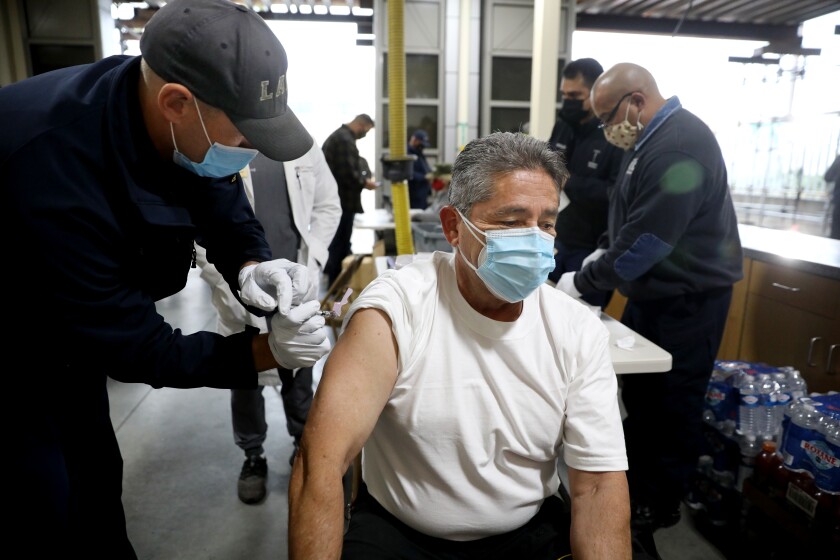 A Los Angeles fire inspector is given a Moderna COVID-19 vaccination at Station 4 on Dec. 28.