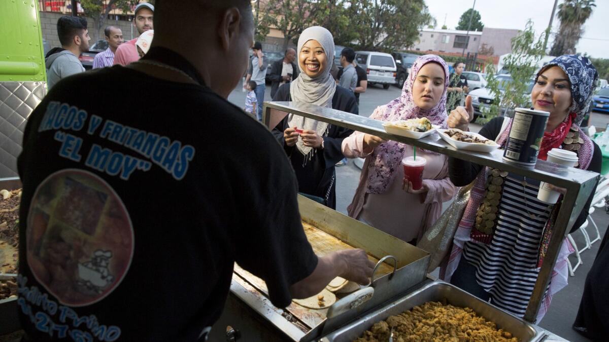 People line up at a taco truck in the parking lot of the Islamic Center of Santa Ana for a 'Taco Truck at Every Mosque' event for iftar.