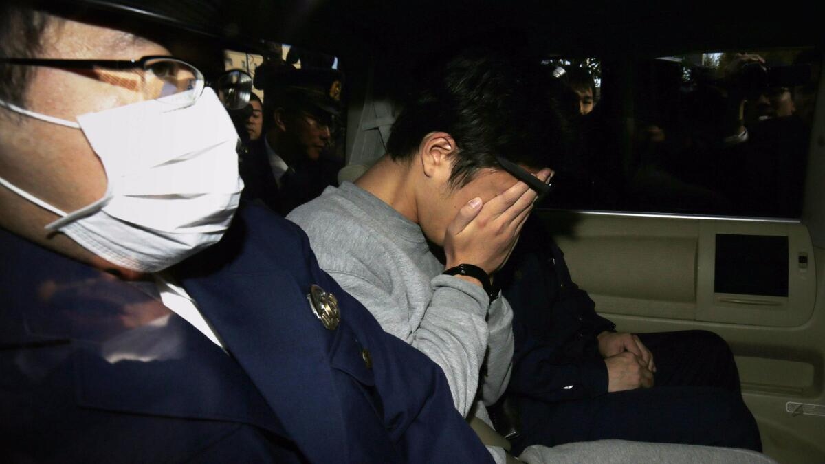 Takahiro Shiraishi covers his face as he is transported to a prosecutor's office from a police station in Tokyo on Nov. 1. Shiraishi was arrested after police found nine dismembered corpses rotting in his apartment.