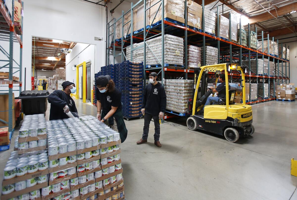 Los trabajadores clasifican los alimentos en el Banco de Alimentos de San Diego de Jacobs & Cushman el 14 de abril de 2020.
