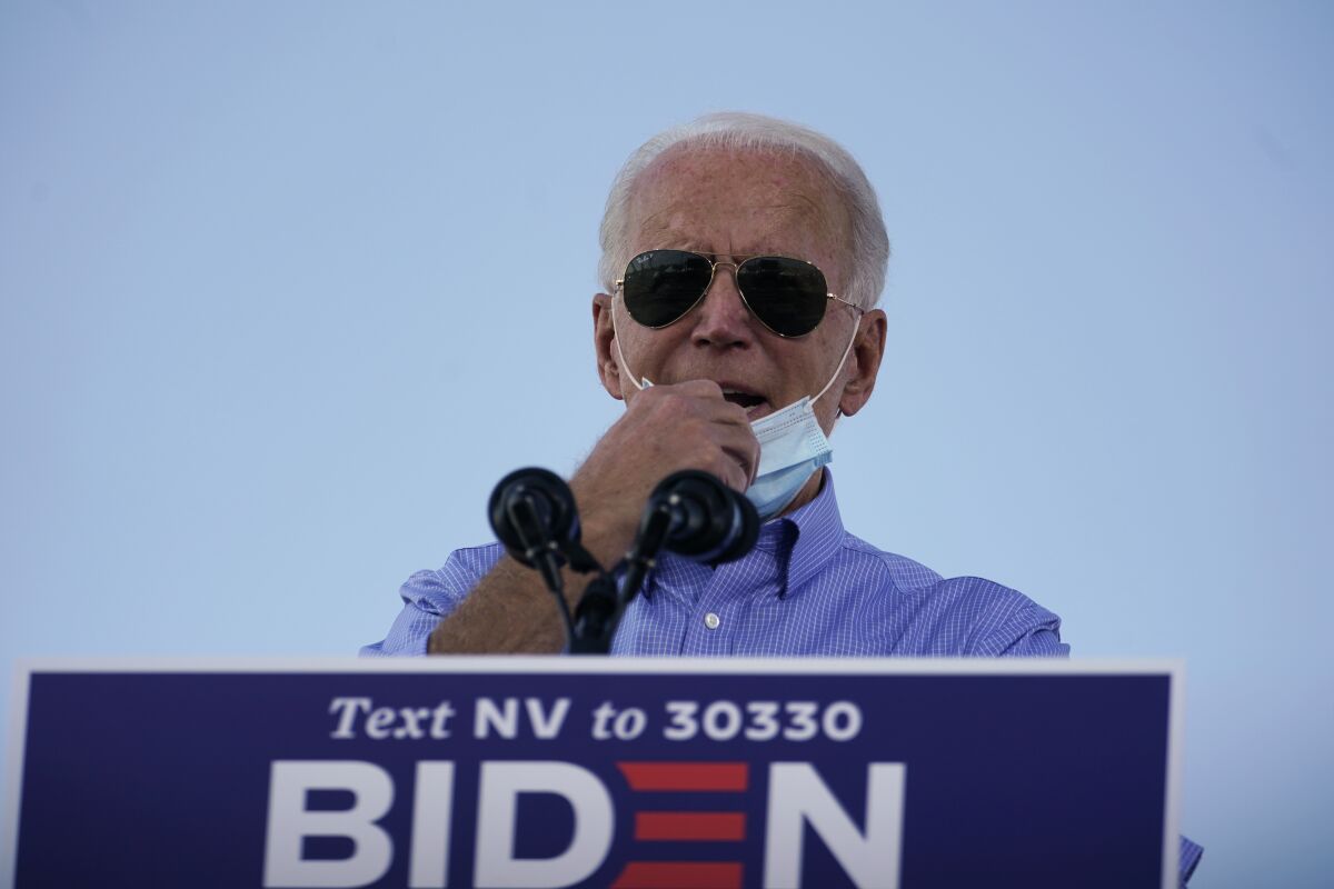 Joe Biden pulls down his protective mask as he speaks at a drive-in event Friday in Las Vegas.