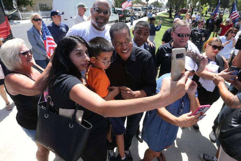 Pardeep Takhar and her five-year-old son Isaac Romer take a photograph with gubernatorial candidate Larry Elder as he arrived to speek to supporters during a campaign stop at Jastro Park in Bakersfield on Thursday afternoon.