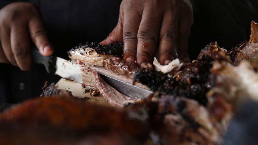 Kevin Bludso cuts barbecued meat at his Compton restaurant Bludso's BBQ.