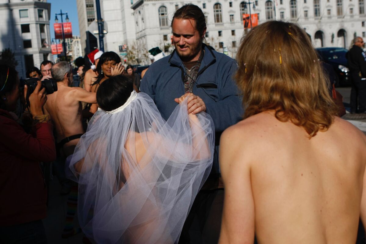 Ein Mann bei einer Hochzeit im Freien hält die Hand einer Frau, die einen Schleier trägt