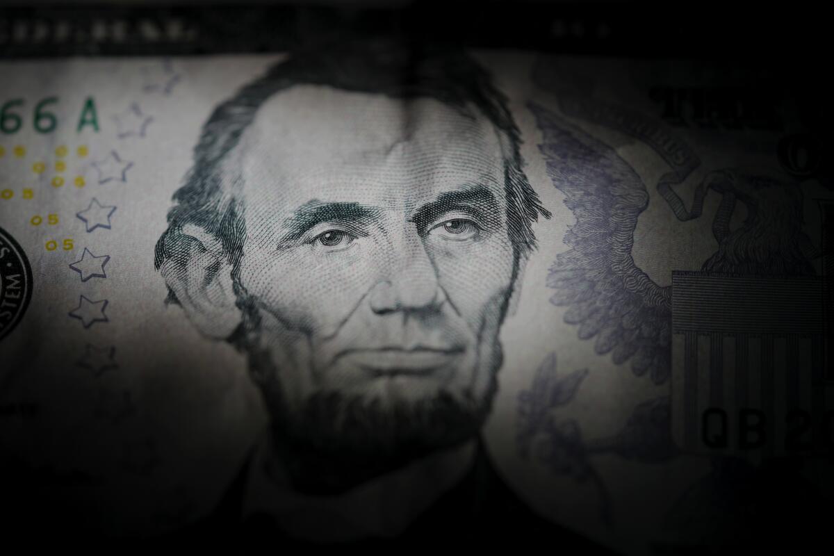 A partly darkened portrait of Abraham Lincoln on a U.S. $5 bill.