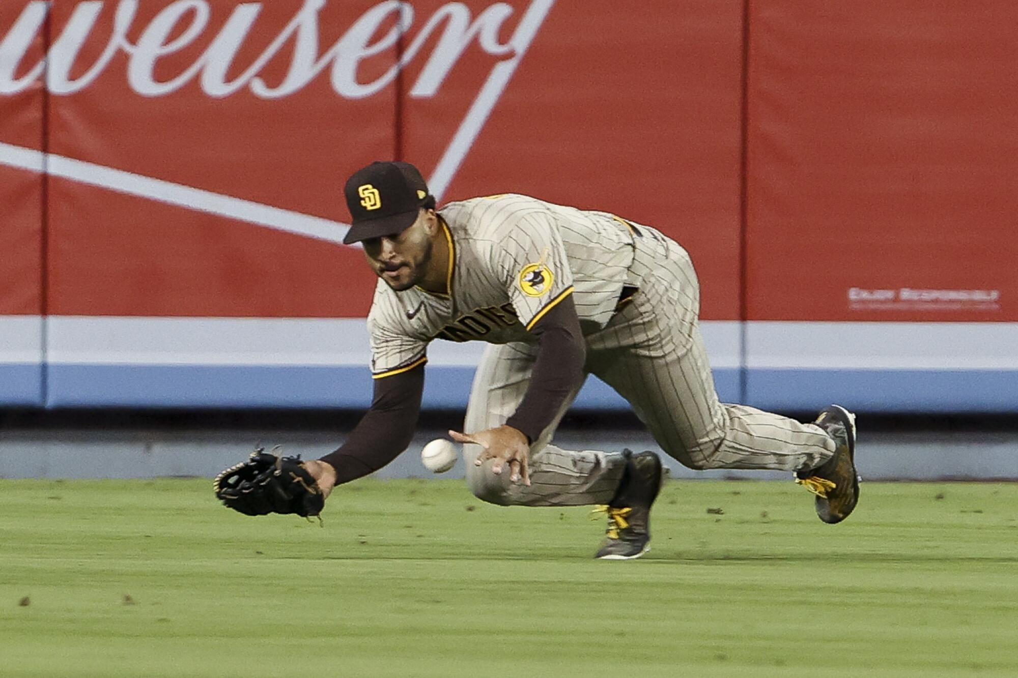  Padres center fielder Trent Grisham dives for ball hit by Dodgers' Mookie Betts during the seventh inning.