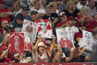 Fans hold up pictures of Los Angeles Angels' Shohei Ohtani and his interpreter Ippei Mizuhara.