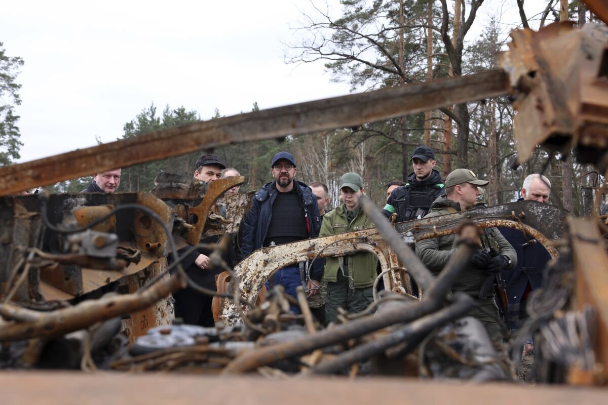In this image provided by the European Council, European Council President Charles Michel, center, looks at destroyed vehicles as he is given a tour of the region of Borodyanka, Ukraine, Wednesday, April 20, 2022. (Dario Pignatelli/European Council via AP)