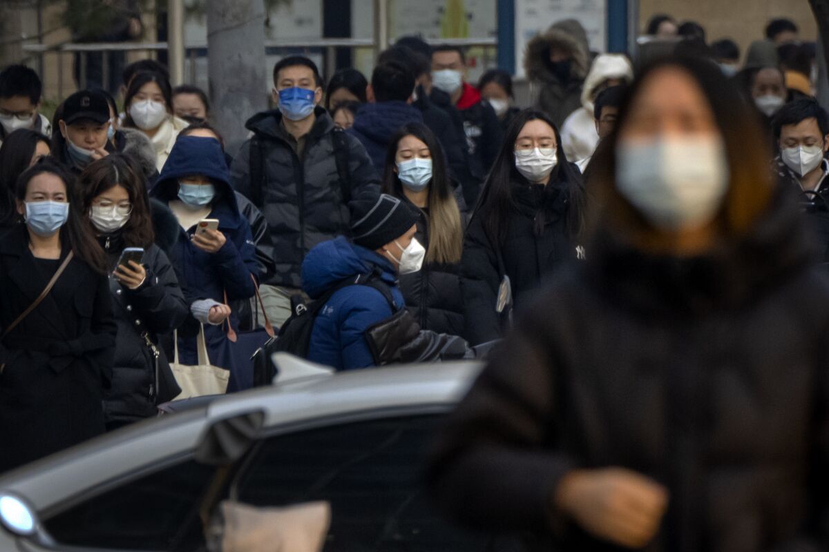 Commuters wearing surgical masks walk along a street 