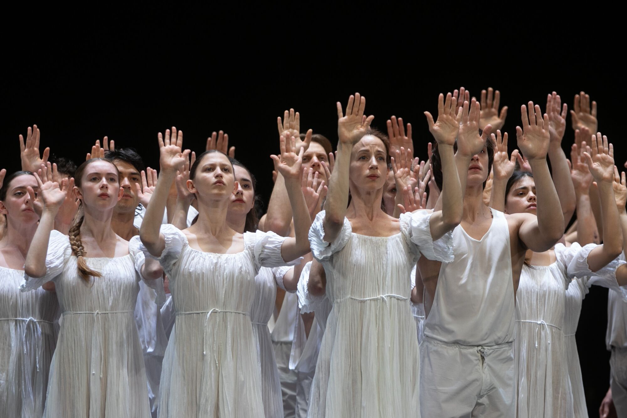 A group of dancers raise both arms.