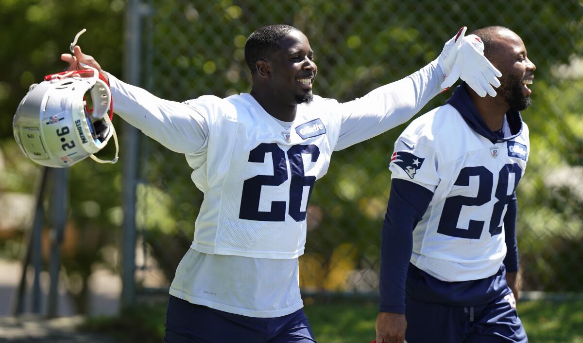 New England Patriots running back Sony Michel raises his arms while stepping on the field with James White.