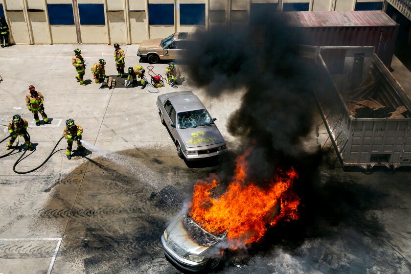 Recruits put out a simulated car fire after passing their final tests.