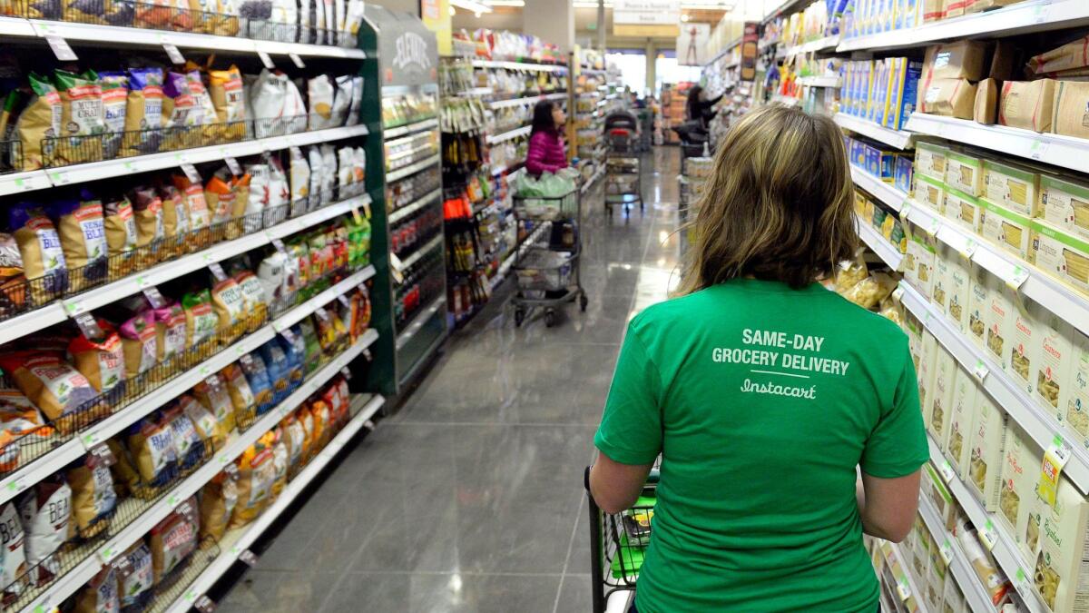 An Instacart shopper looks for groceries at a Whole Foods store in Denver. (Cyrus McCrimmon / Denver Post via Getty Images)