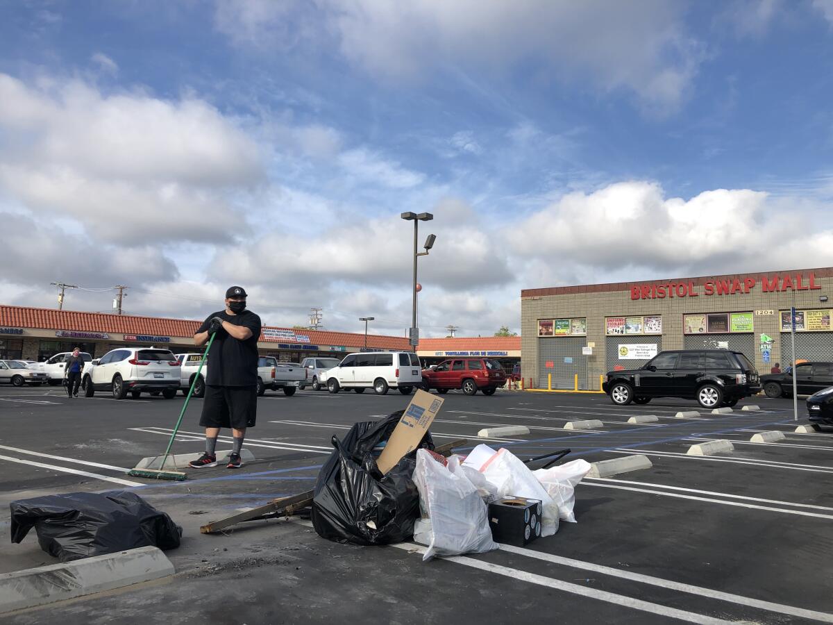 Arthur Borboa, 33, cleans up debris outside the Bristol Swap Mall in Santa Ana, the morning after a protest.