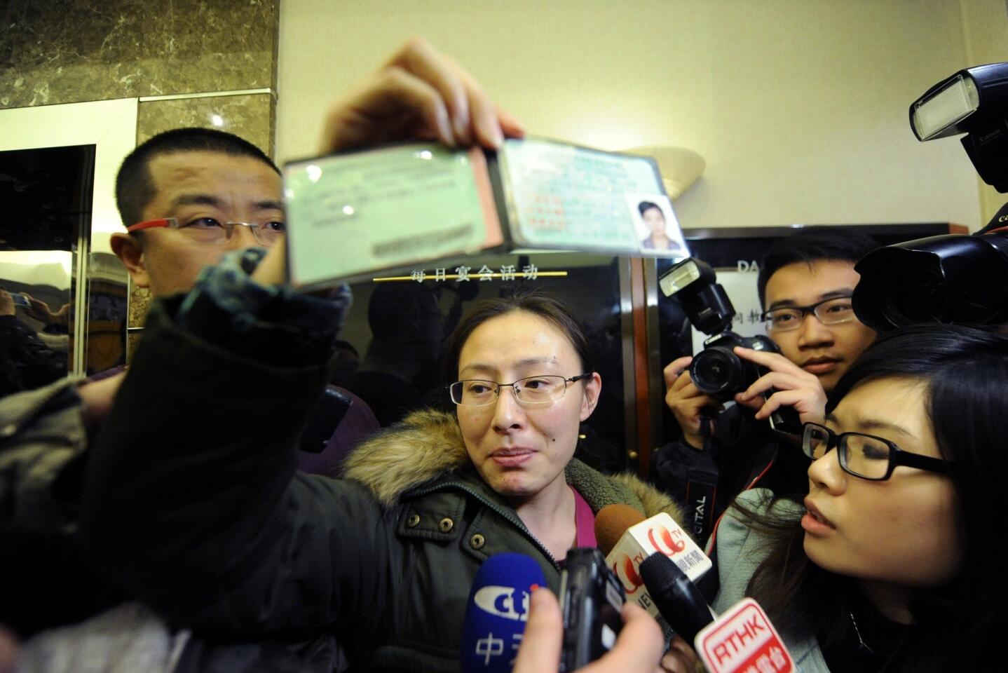 A woman displays the driver's licence of a friend who may be a passenger on board the missing Malaysia Airlines flight at a hotel in Beijing.
