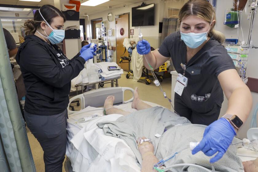 Victorville, CA - January 27: Nurse Amber McCarter, left, and traveling nurse Rebekah Seyler attend to a COVID19 patient in emergency room at Desert Valley Hospital on Thursday, Jan. 27, 2022 in Victorville, CA. (Irfan Khan / Los Angeles Times)
