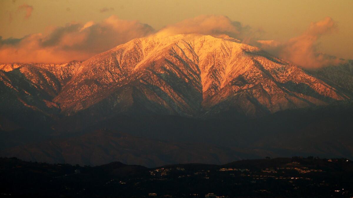 The setting sun casts a golden glow on the snow-covered peaks of Mt. Baldy in 2016. This weekend, snow shut down a main road, stranding scores of people on the mountain.