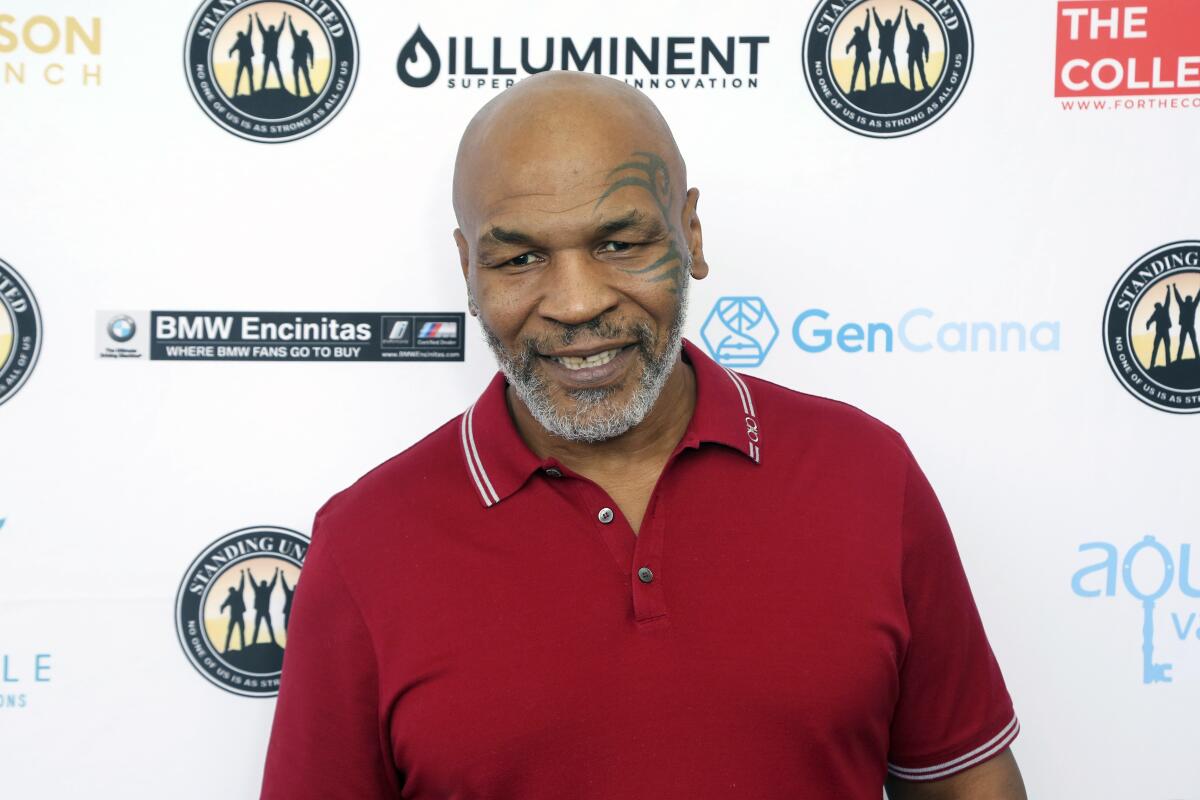 Mike Tyson smiles in a short-sleeved collared shirt.