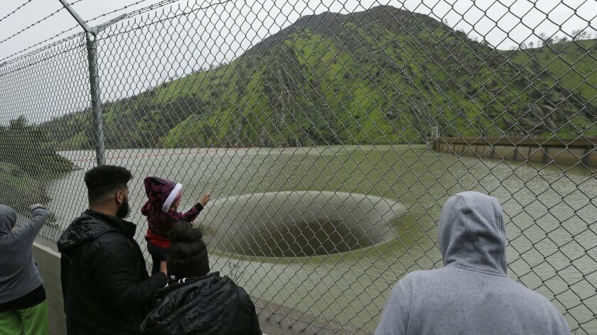 People watch water flow into the iconic spillway at the Monticello Dam in 2017.