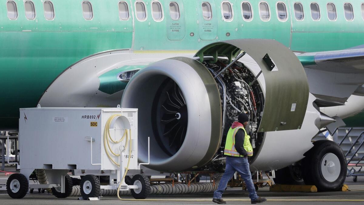 A worker walks past an engine on a Boeing 737 Max 8 airplane being built for American Airlines at Boeing's Renton, Wash., assembly plant.