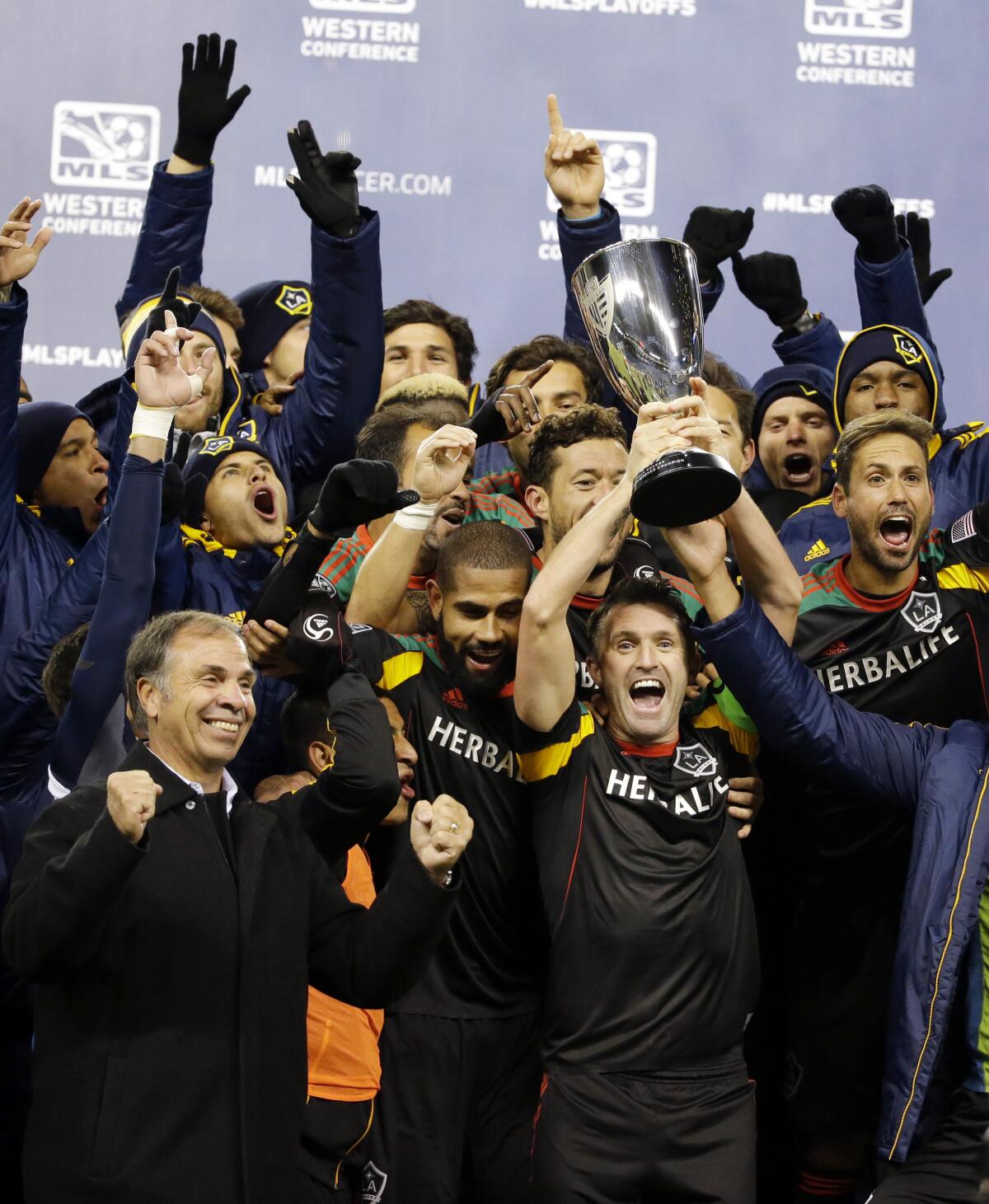 Galaxy coach Bruce Arena, lower left, cheers as Robbie Keane, center, lifts up the western conference trophy 