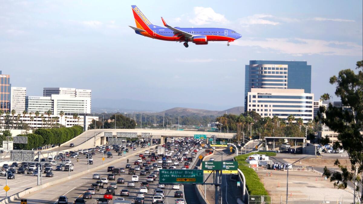 A jet flies over the 405 Freeway as it approaches the runway at John Wayne Airport.