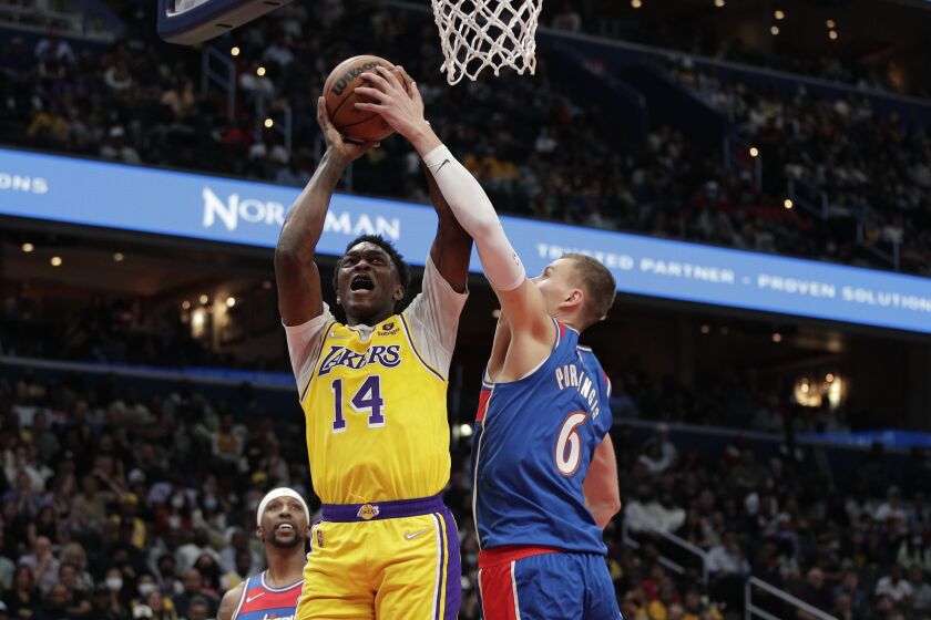 Los Angeles Lakers Stanley Johnson (14) is fouled by Washington Wizards' Kristaps Porzingis (6) during the second half of an NBA basketball game Saturday, March 19, 2022, in Washington. (AP Photo/Luis M. Alvarez)
