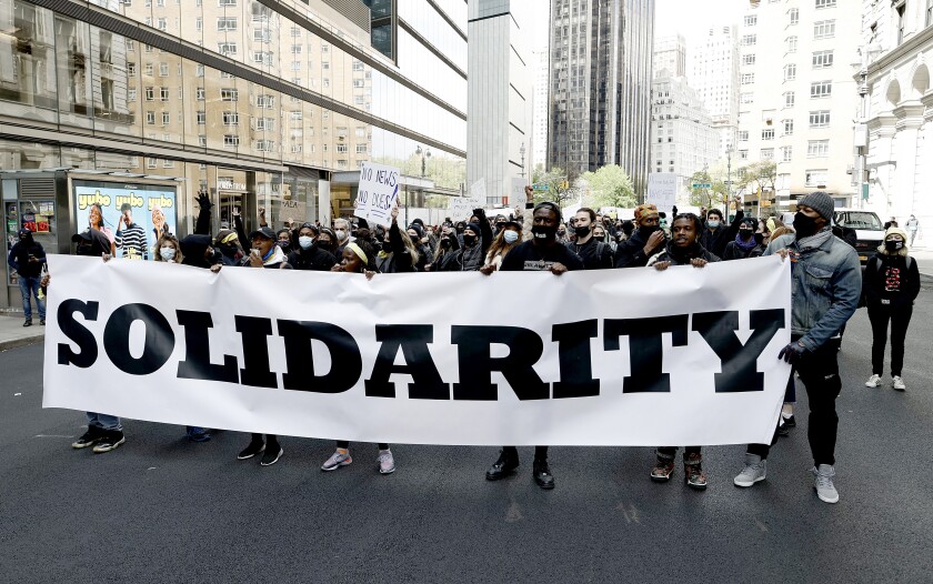 Protesters march down the street holding a Solidarity banner in front of them.