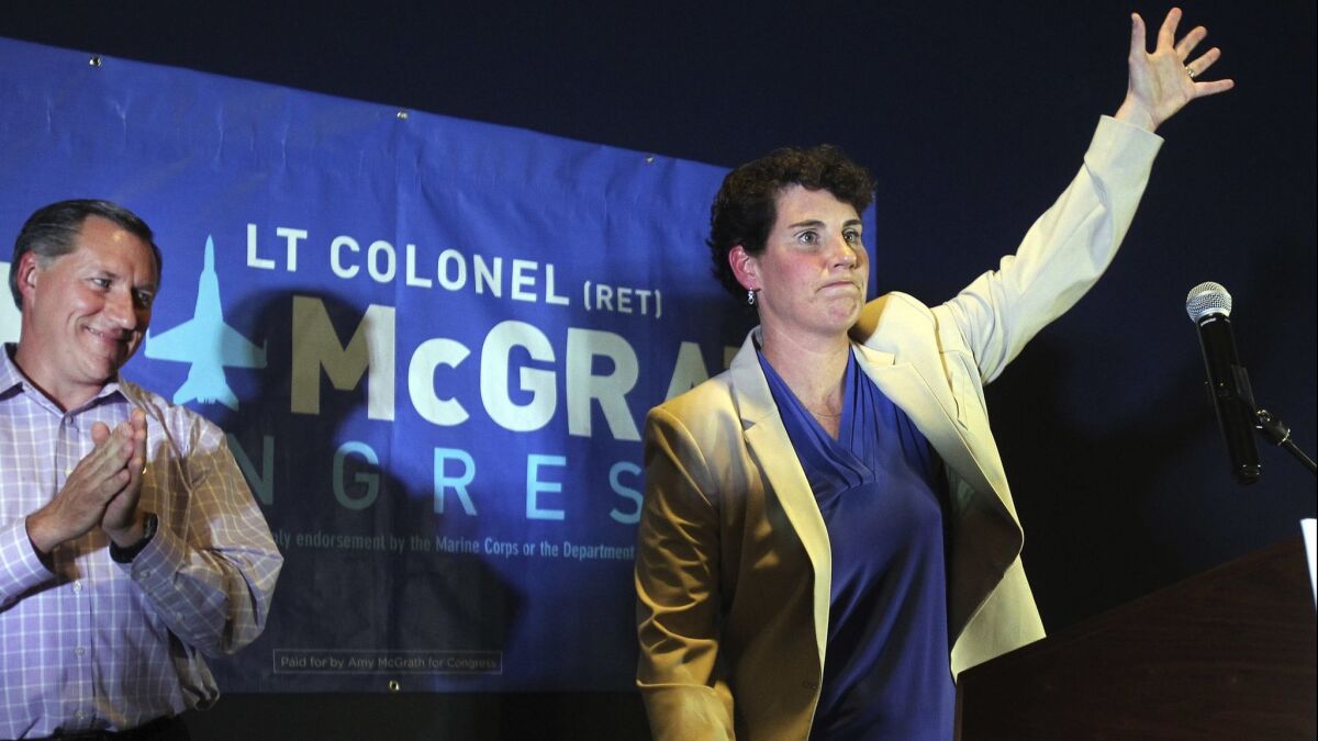 Amy McGrath, right, with her husband, Erik Henderson, waves to supporters after being elected as the Democratic candidate for Kentucky's 6th Congressional District in Richmond, Ky.