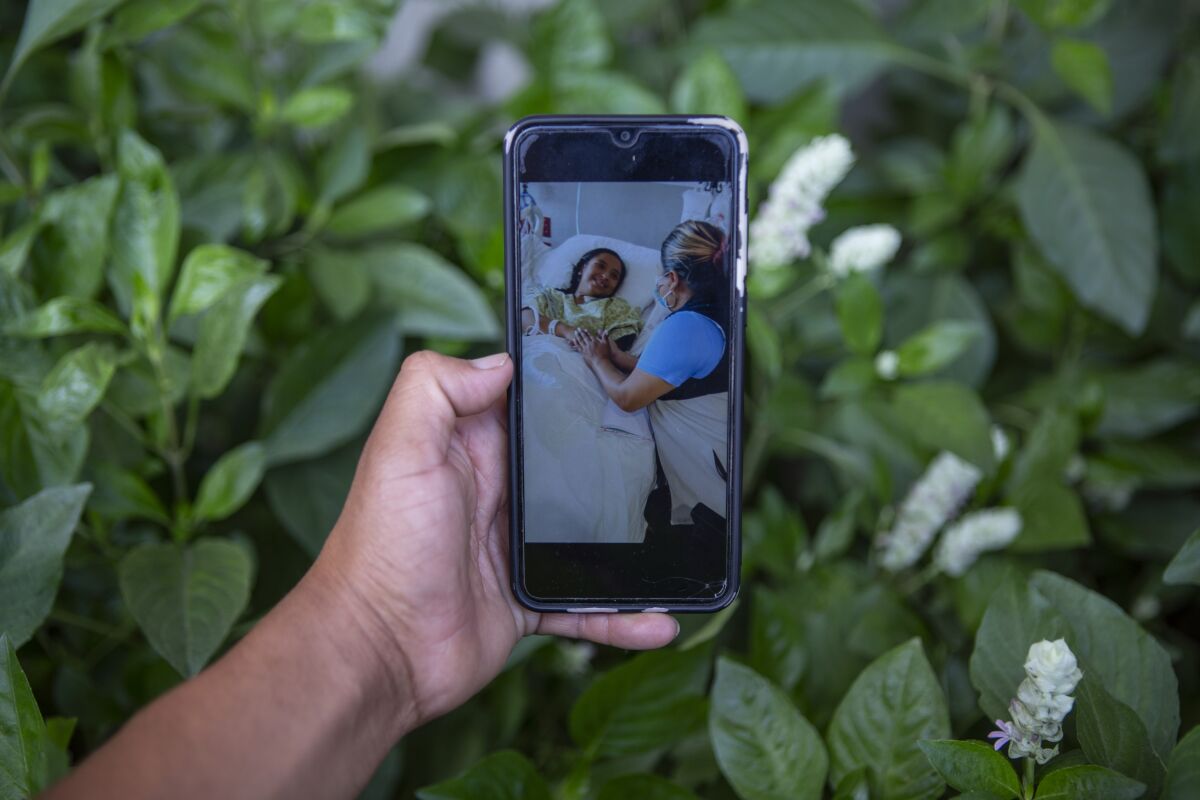 Mynor Cardona shows a photo on his cellphone of her daughter, Yenifer Yulisa Cardona Tomás, at the hospital while receiving a visit, in Guatemala City, Monday, July 4, 2022. Yenifer Yulisa Cardona Tomás is one of the survivors of the more than 50 migrants who were found dead inside a tractor-trailer near San Antonio, Texas. (AP Photo/Oliver de Ros)