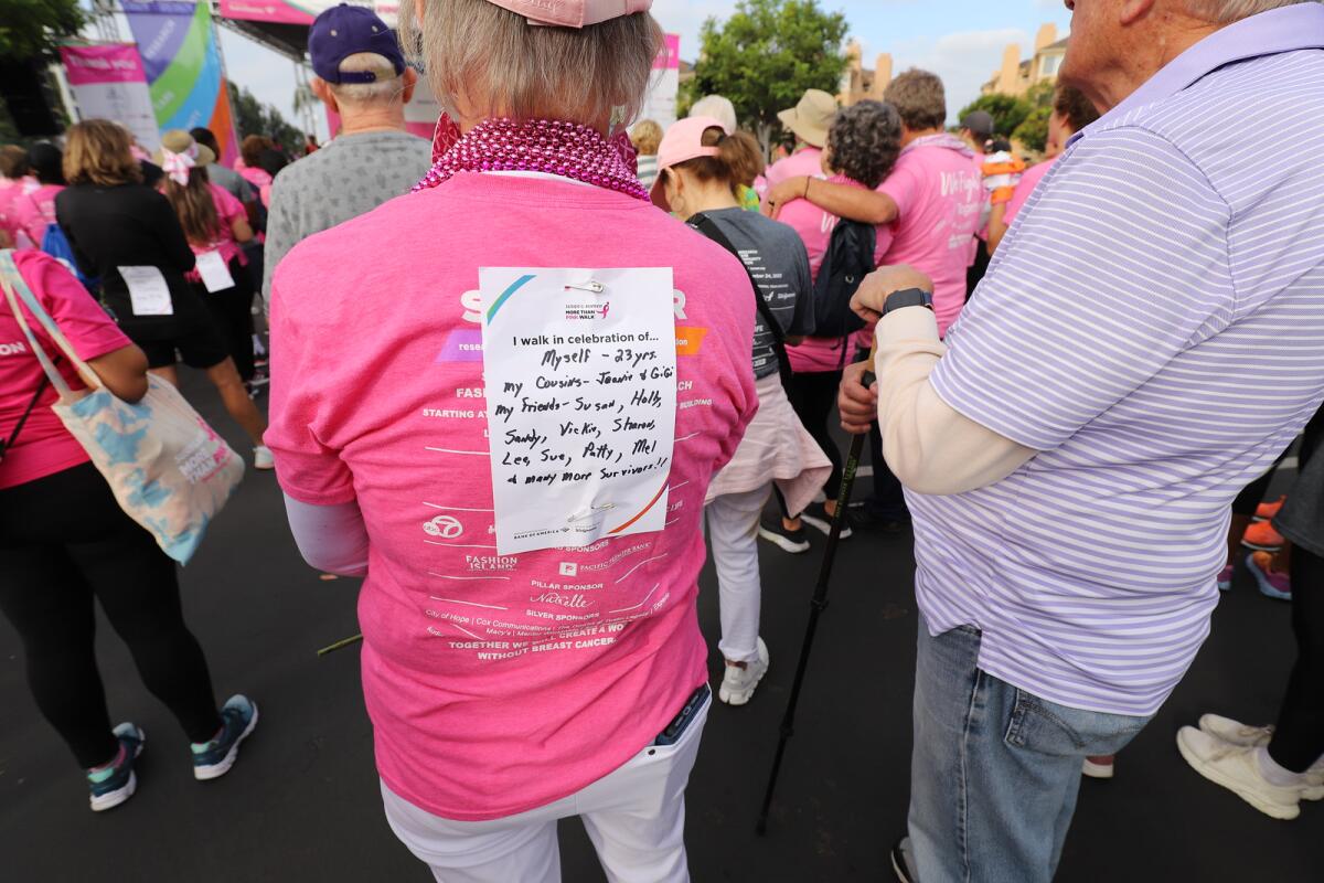 An unidentified 23-year survivor of breast cancer wears the “I walk in celebration of ...” back sign.