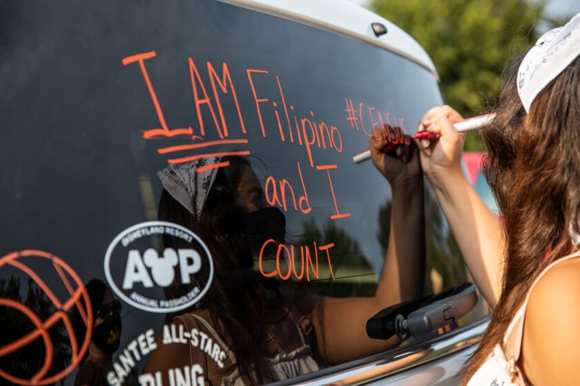 Alexis Hernandez, 18, writes on the back windshield of an SUV before a caravan event that encouraged participation in the 2020 Census.
