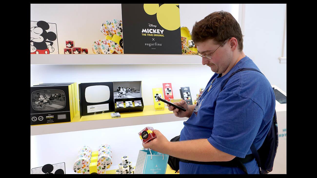 Matthew Hopkins, 23 of N. Hollywood, takes a photo of a box of Disney Mickey The True Original x Sugarfina candy at the Americana at Brand location in Glendale on Wednesday, Aug. 22, 2018. Sugarfina is offering a line of confections for the 90th anniversary of Mickey Mouse.