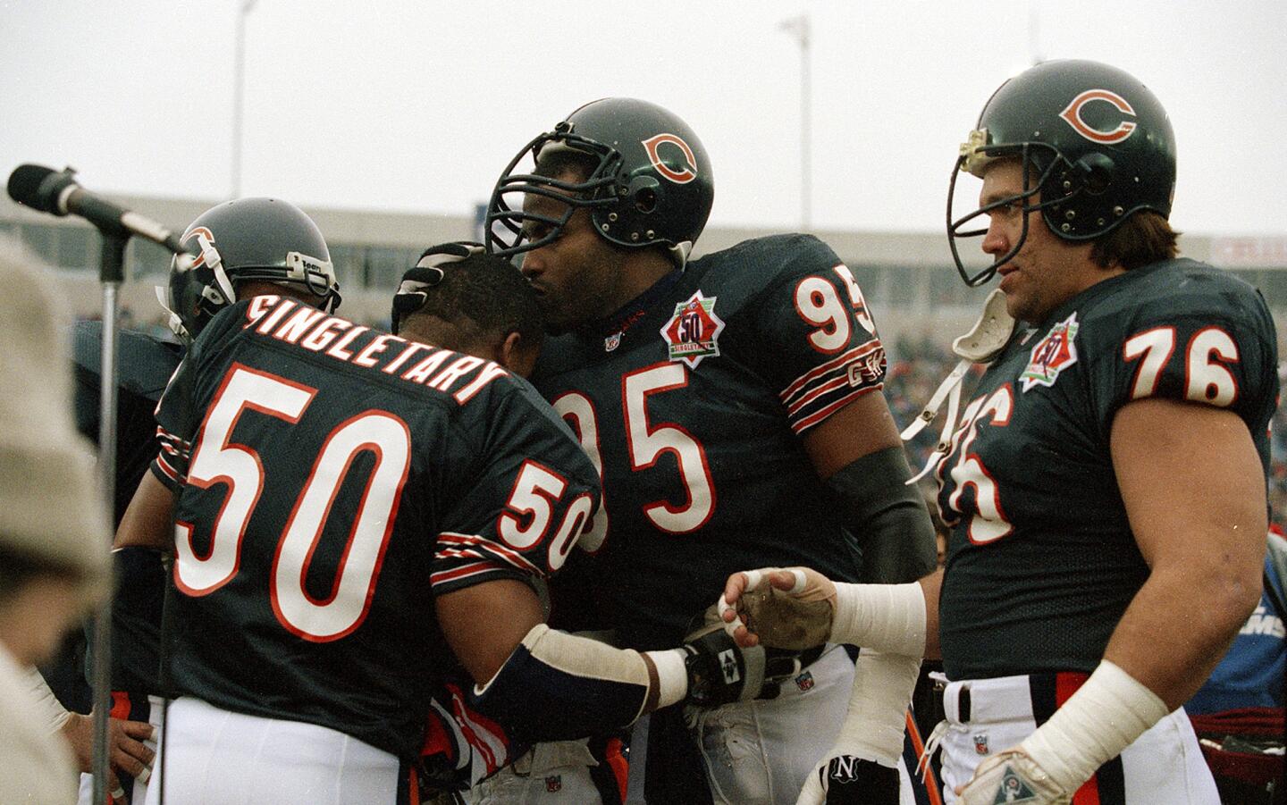 Richard Dent kisses Mike Singletary's head as Steve McMichael watcges during a ceremony at Soldier Field on Dec. 13, 1992, before Singletary's final game before retirement.