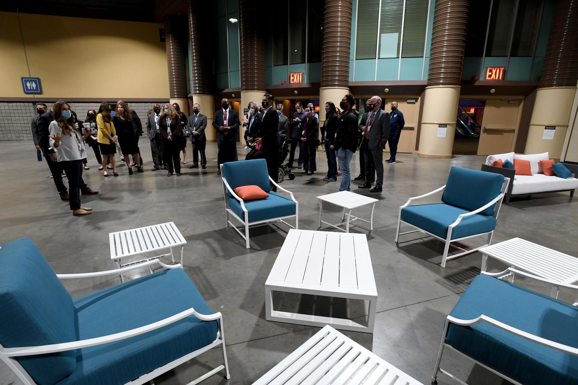 Officials are seen in the background of an area with couches, chairs and tables